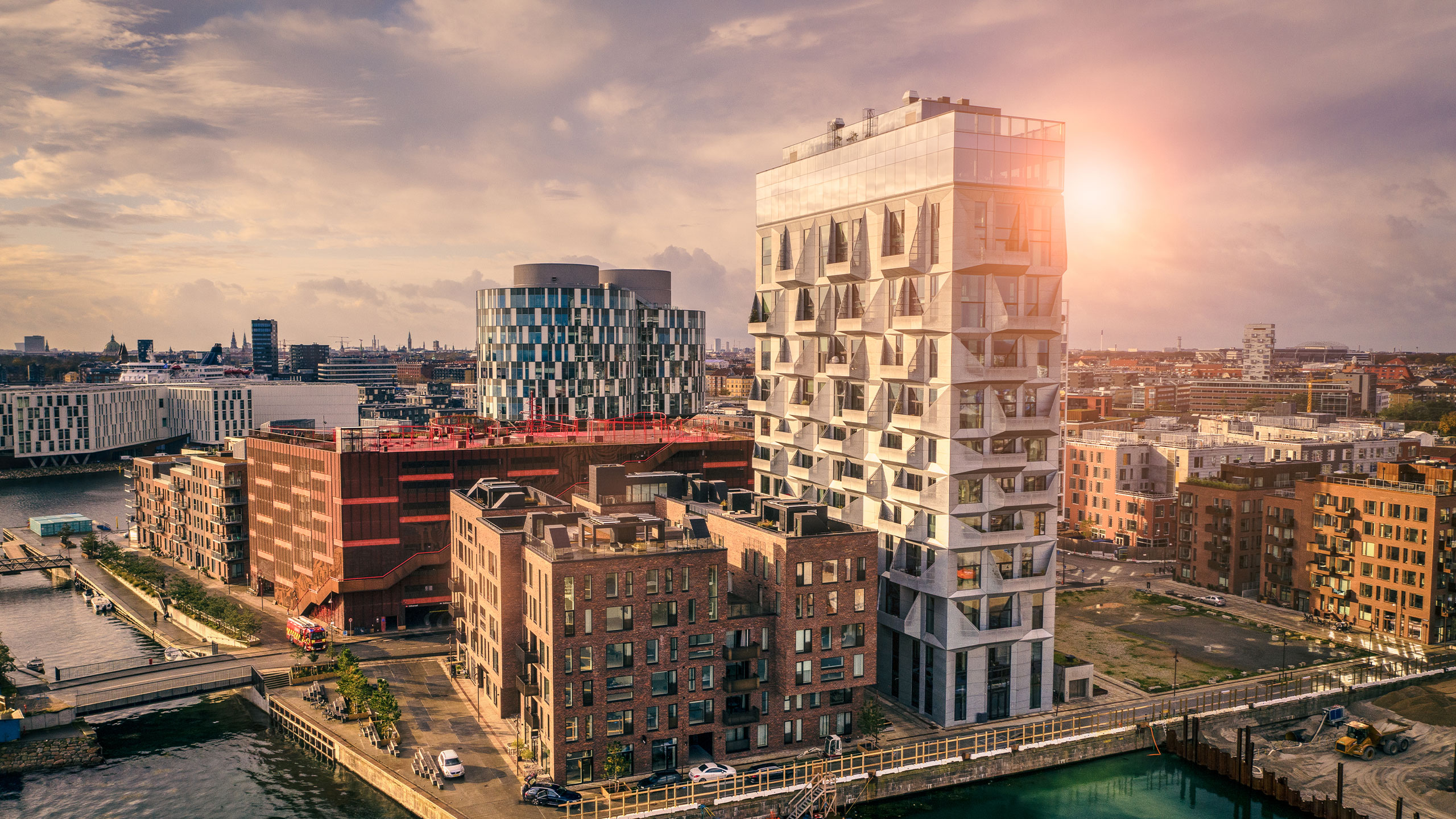 Overblik over by ved solopgang i fokus forskellige kontorbygninger ved havnefront